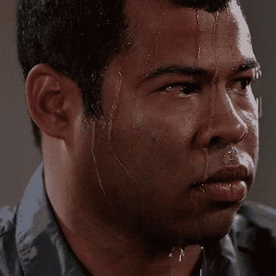 A imagem retrata um home negro com uma camisa socieal suando muito e com feições tensas.